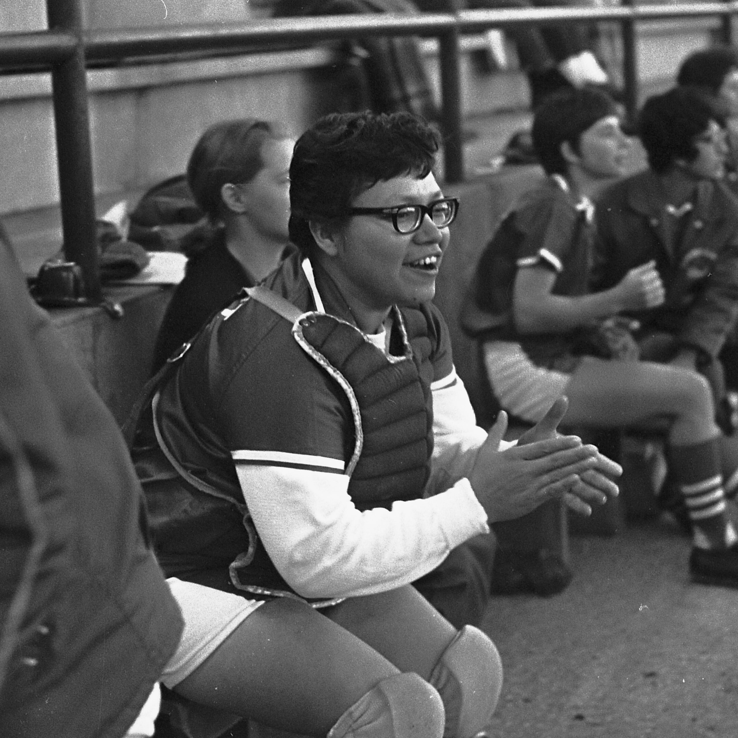 Black and white photo of Phyllis Bomberry sitting on a bench and cheering her team on.